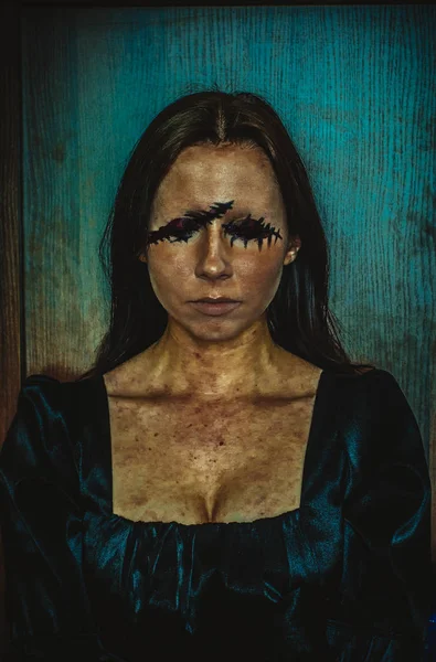 Ritratto inquietante di giovane donna senza occhi su sfondo azzurro ruvido — Foto Stock