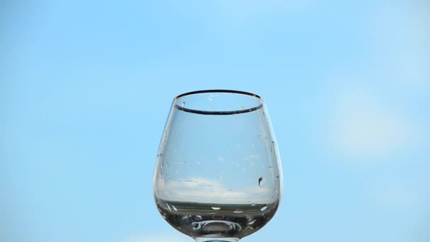 L'eau se déverse dans un verre transparent sur un fond bleu ciel. Concept de source de vie et de santé 