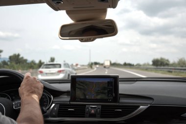 Holding bir direksiyon simidi, gezinti ekran bir araba otomobiller, hareketli bir karayolu üzerinde genç bir adam