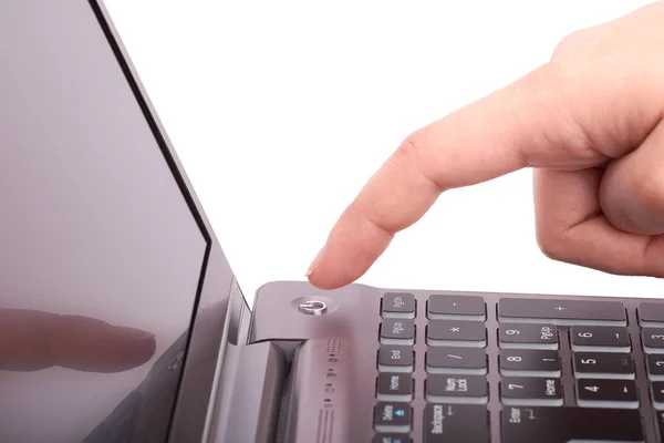 Крупный план женской руки с указательным пальцем, нажатие кнопки старта серебряного ноутбука с черной клавиатурой и дисплеем. Включает или выключает блокнот. Изолированный на белом фоне . — стоковое фото