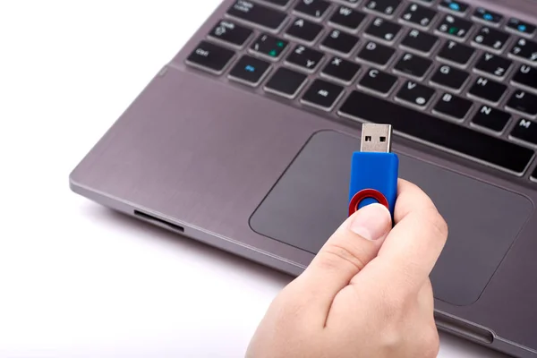 Uma mulher tem uma pen drive USB azul na mão. laptop prata — Fotografia de Stock
