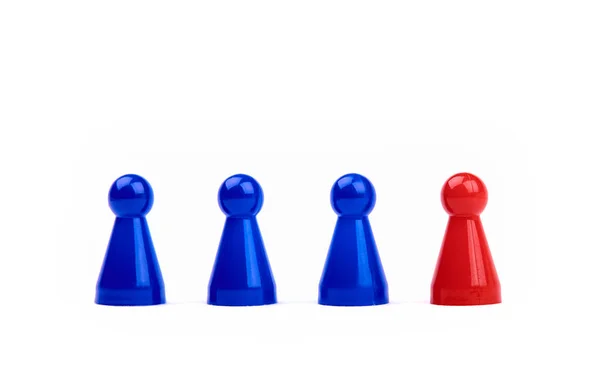 Three plastic blue game pieces as a team and next to them a red piece as leader or different. Isolated on white background. — Stock Photo, Image