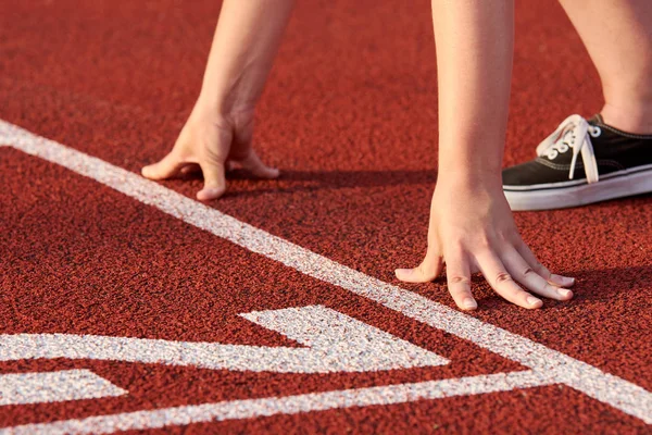 View of female athlete at race start. It stands on a red tartan