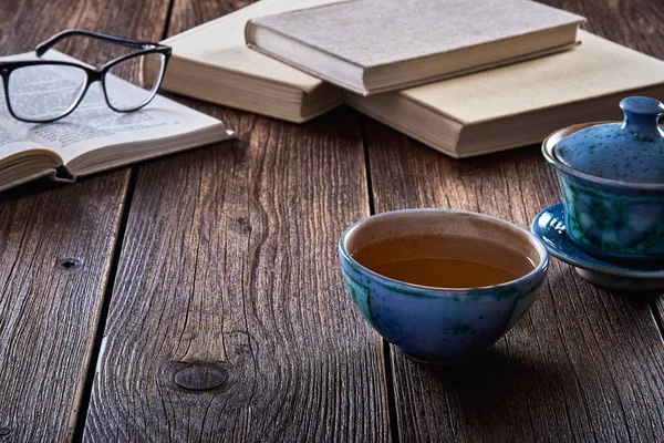 Bodegón con mesa de madera vieja, taza de té y libros . — Foto de Stock