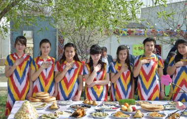 Geleneksel elbiseler ve Ulusal yemeklerin bir tabloyla Özbek kızlar