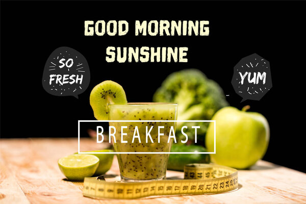 fresh fruit smoothie in glass with piece of kiwi, limes and measuring tape on tabletop, with "good morning sunshine" and  "breakfast" letterings