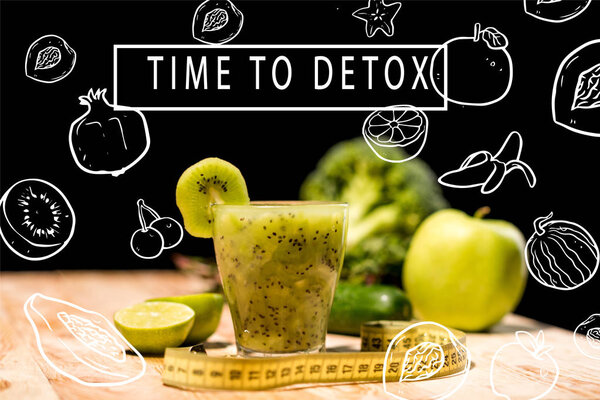 fresh fruit smoothie in glass with piece of kiwi, limes and measuring tape on tabletop, with "time to detox" inspiration with illustration
