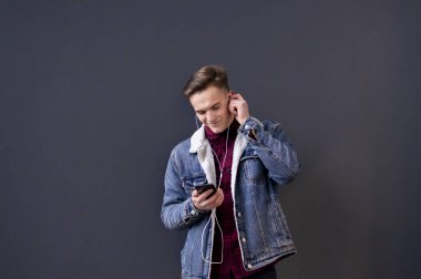 Kot ceketli ve gömlekli genç adam kulaklıkla müzik dinliyor ve video bağlantısı üzerinden iletişim kuruyor.