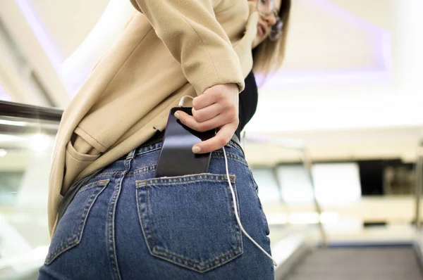 Девушка получает черный телефон из задних карманов — стоковое фото