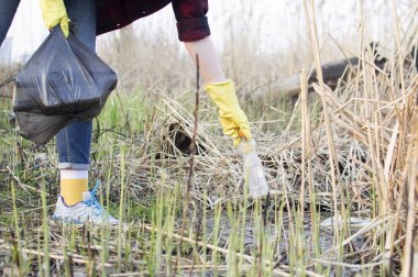 kız çöp temizler, çöp torbasına plastik bir şişe atar