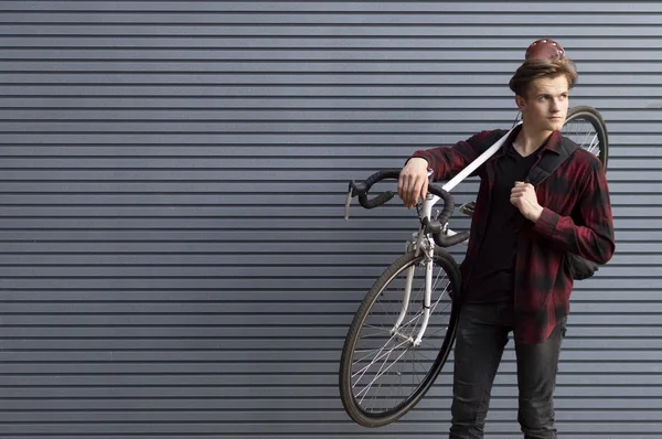 Young handsome guy carries a broken bike on his shoulders against the wall, the student goes on foot — Φωτογραφία Αρχείου