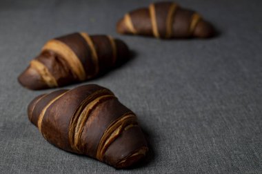 bir arka plan üzerinde yatan üç çikolata kahverengi kruvasan, sağdaki arka plan boş