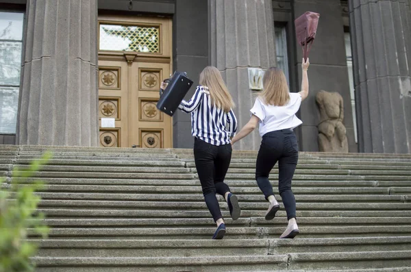 kız öğrenciler okula giderler, üst kata çıkarlar, el ele tutuşmuşlar, kız arkadaşları derslere koşarlar.