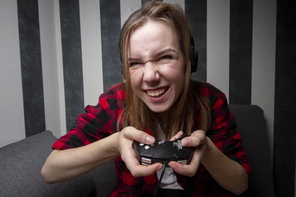 Jovem menina agressiva joga jogos de computador no joystick à noite no quarto, ela grita no console — Fotografia de Stock