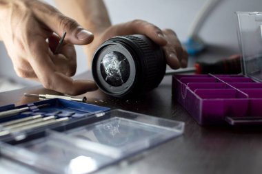 kırık lens araçları ile tamir masasında yatıyor, kırık bir lens yakın çekim, bir adam onarım fotoğraf ekipmanları