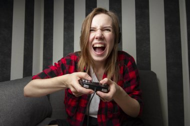 agresif kız kanepede oturur ve joystick video oyunları oynar, o çığlıklar ve konsolda kaybeder