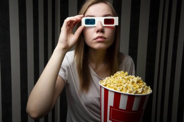 genç kız bir film izlerken ve gece çizgili bir duvara karşı 3d gözlük giyen patlamış mısır yeme, o duygusal ve şaşırmış
