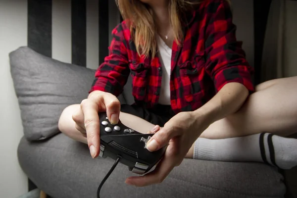 Young girl plays on the console, she sits at home on the couch and holds the joystick, close-up of the device — Stock Photo, Image