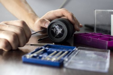 kırık lens araçları ile tamir masasında yatıyor, kırık bir lens yakın çekim, bir adam onarım fotoğraf ekipmanları