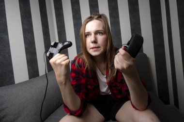 agresif kız kanepede oturur ve joystick video oyunları oynar, o çığlıklar ve konsolda kaybeder