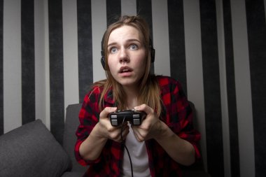 genç kız kanepede oturur ve joystick üzerinde konsol oynar, o video oyunları odaklanmıştır