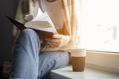 genç kız bir battaniye ile kaplı pencerenin yanında evde oturur, bir kitap okur ve çay içecekler, metin için boşluk kopyalamak