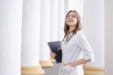 koridorda duran bir tıp üniversitesinde genç kız öğrenci, hastane yakınında çekici bir hemşire portresi, üniformalı bir stetoskop ile mutlu kadın doktor