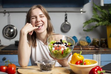 Genç kız mutfakta vejetaryen salata hazırlar, o zeytin tadı, sağlıklı gıda hazırlama süreci