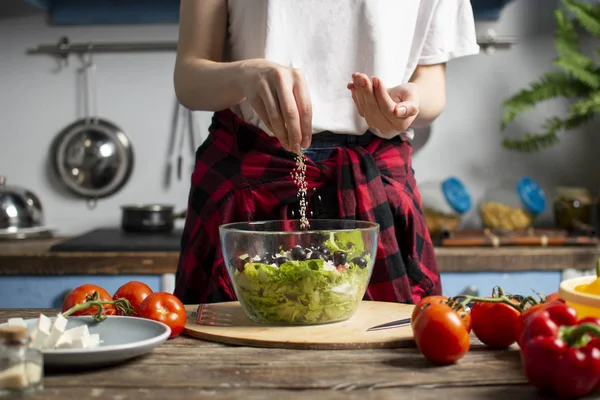Genç kız mutfakta vejetaryen salata hazırlar, o tuzlar ve baharat ekler, sağlıklı gıda hazırlama süreci
