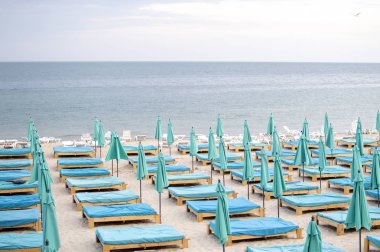 denize yakın birçok boş plaj yatağı, insanlar olmayan bir plaj, terk edilmiş bir dinlenme yeri