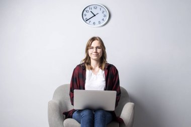 yumuşak rahat bir sandalyede oturan bir dizüstü bilgisayar ile genç kız ve fazla mesai, bir kadın geç akşam bir bilgisayar kullanarak, o freelancing ve baskı metin, kopya alanı