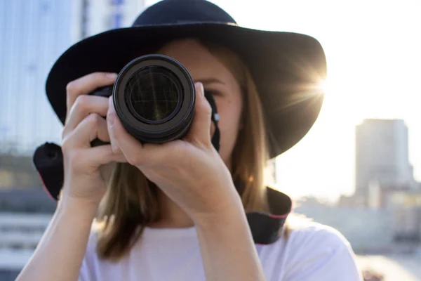 Retrato de una fotógrafa, una mujer con una cámara fotográfica moderna sobre el telón de fondo de una puesta de sol en la ciudad —  Fotos de Stock
