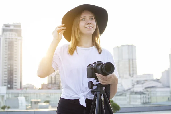 Fotografin mit Kamera und Stativ auf einem Hintergrund der Stadt, sie fotografiert bei Sonnenuntergang, eine Frau dreht ein Video — Stockfoto