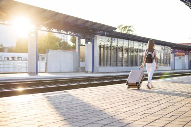 çekici kız istasyonda bagaj ile ayakta ve tren bekliyor, öğrenci bir geziye gidiyor, o platform boyunca yürüyor, kopya alanı