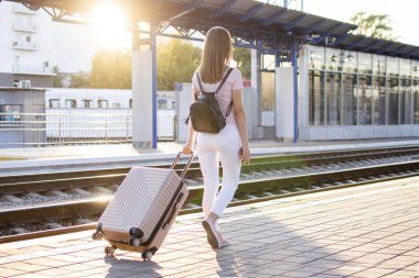 çekici kız istasyonda bagaj ile ayakta ve tren bekliyor, öğrenci bir geziye gidiyor, o platform boyunca yürüyor, kopya alanı