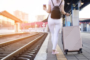 çekici kız istasyonda bagaj ile ayakta ve tren bekliyor, öğrenci bir geziye gidiyor, o kahve ile platform boyunca yürüyor, kopya alanı