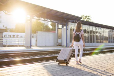 çekici kız istasyonda bagaj ile ayakta ve tren bekliyor, öğrenci bir geziye gidiyor, o platform boyunca yürüyor, kopya alanı