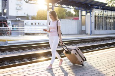 çekici kız istasyonda bagaj ile ayakta ve tren bekliyor, öğrenci bir geziye gidiyor, o platform boyunca yürüyor, kopya alanı