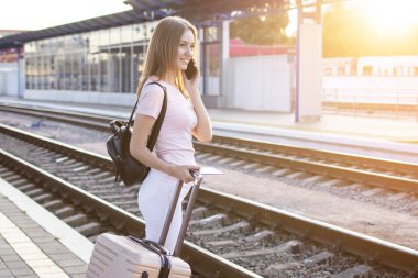 kız bir bavul ile istasyonun platformu üzerinde duruyor ve bir tren bekliyor, bir öğrenci seyahat, yaz tatili için bırakır, kopya alanı