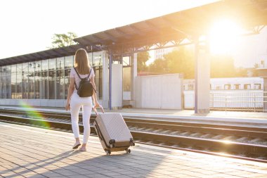 çekici kız istasyonda bagaj ile ayakta ve tren bekliyor, öğrenci bir geziye gidiyor, o platform boyunca yürüyor, kopya alanı