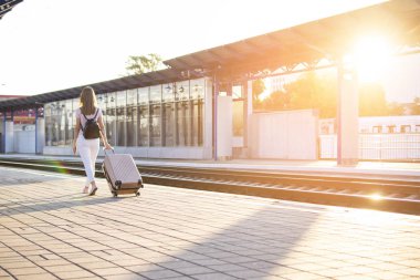 kız bir bavul ile istasyonun platformu üzerinde duruyor ve bir tren bekliyor, bir öğrenci seyahat, yaz tatili için bırakır, kopya alanı