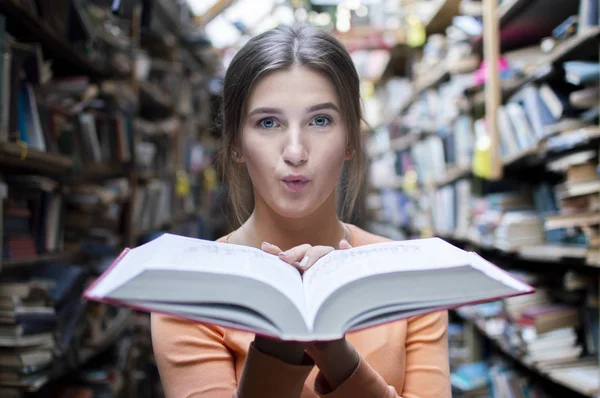 Студентка читает большую старую книгу в библиотеке и выбрасывает пыль крупным планом — стоковое фото