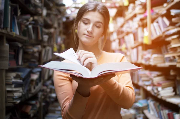 Fille étudiante lit un livre dans la bibliothèque, elle tourne les pages et brosse des informations — Photo