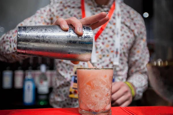 Barman está preparando um coquetel alcoólico em um copo de vidro, ele está decorando a bebida com flores — Fotografia de Stock