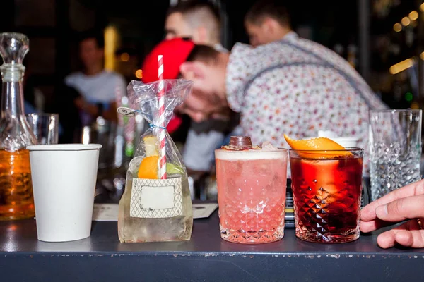 Barman está preparando um coquetel alcoólico em um copo de vidro, ele está decorando a bebida com flores — Fotografia de Stock