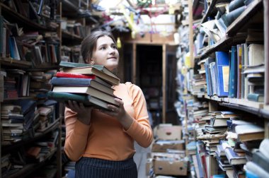kız öğrenci kütüphanede kitap yığını tutar, o edebiyat arar ve okumak için teklif, bir kadın çalışma için hazırlar, bilgi güç, kavram kitapçı