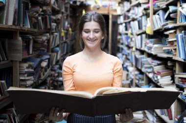 kız öğrenci kütüphanede büyük bir kitap okur, bir kadın çok okumayı seviyor, o kitapraflarında edebiyat arıyor, bilgi güç, kavram