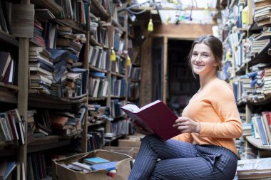 kız öğrenci eski kütüphanede bir kitap okur, bir kadın arşivlerde bilgi arıyor