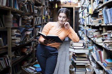 kız öğrenci kütüphanede bir kitap okur, bir kadın çok okumayı seviyor, o kitapraflarında edebiyat arıyor, bilgi güç, kavram