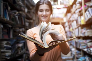 kız öğrenci kütüphanede bir kitap okur, o sayfaları döner ve bilgi fırçalar